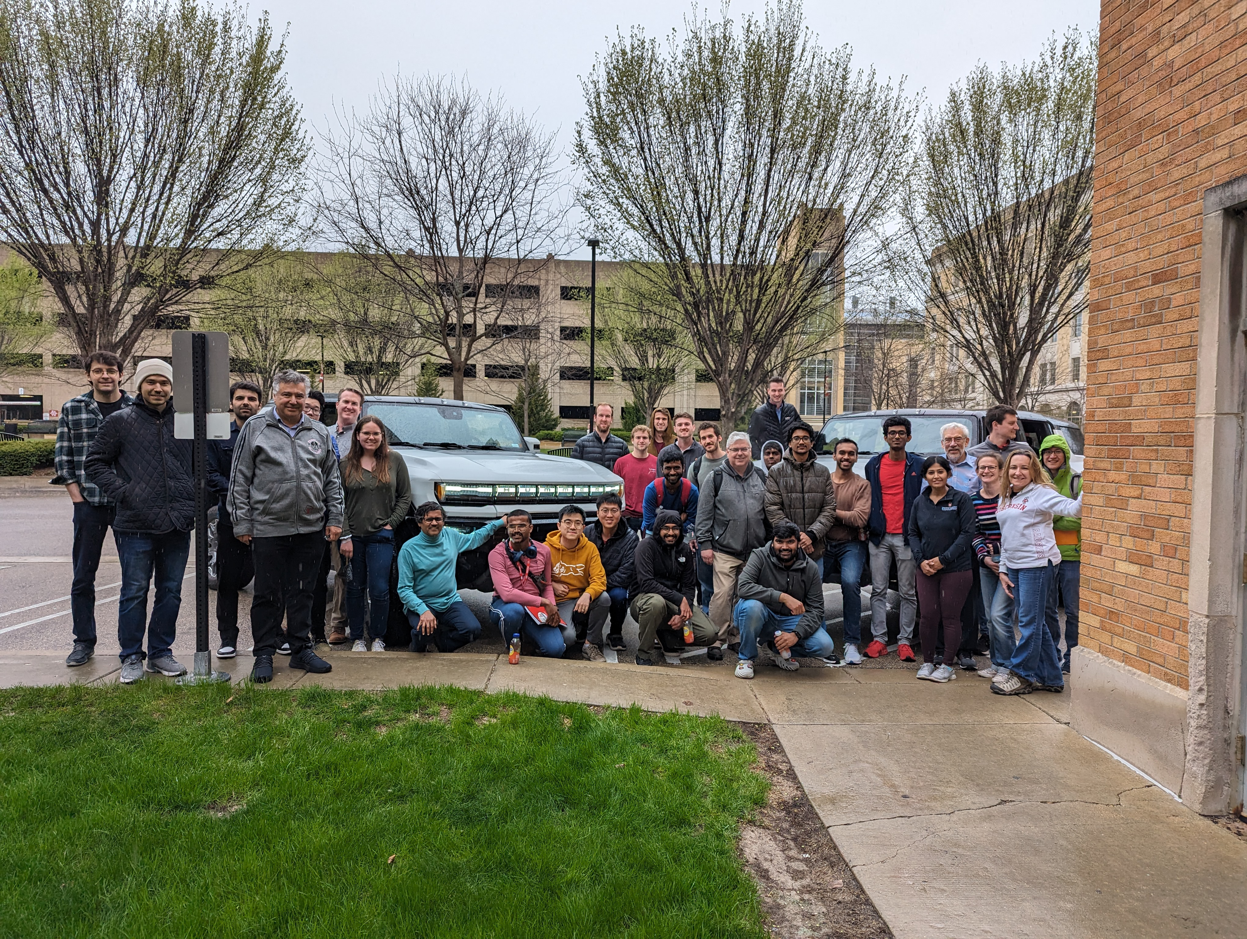 A group photo with WEMPEC staff, students and GM representatives in front of some electric Hummers.
