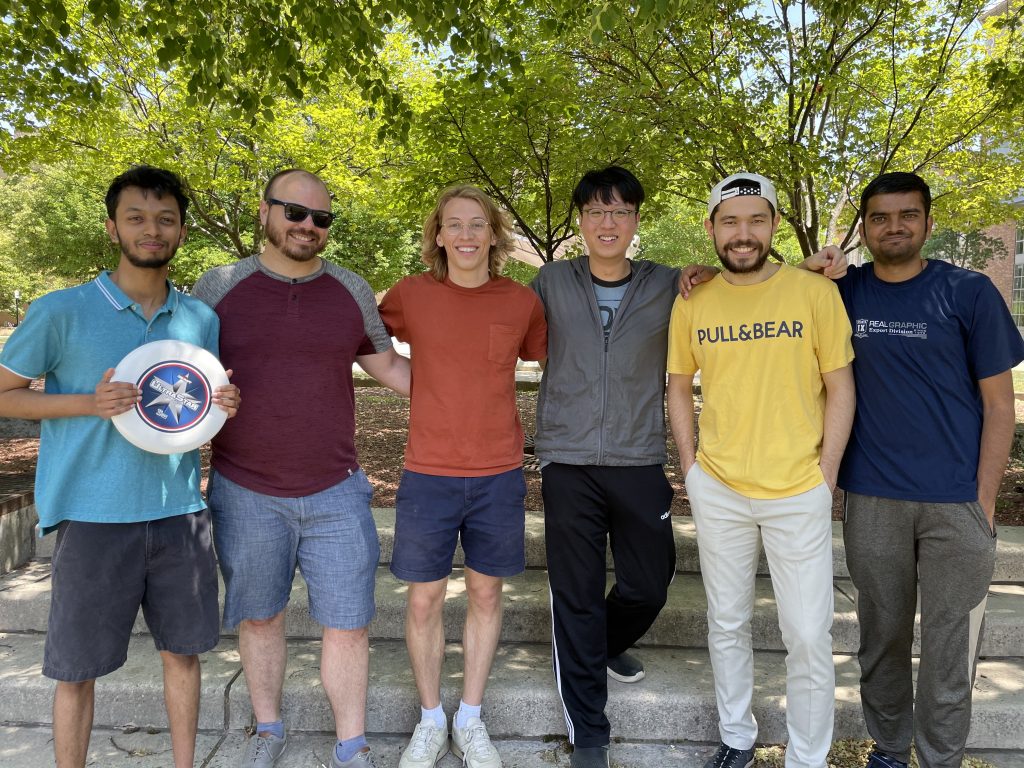 A group of students with casual clothes holding a Frisbee.